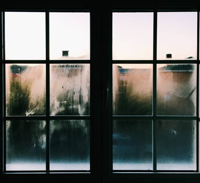 Fenêtre vue de l’intérieur avec de l’eau de condensation sur la surface froide du vitrage.